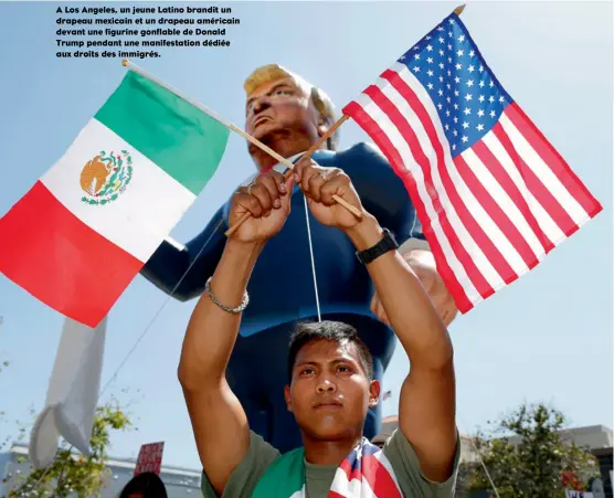  ??  ?? A Los Angeles, un jeune Latino brandit un drapeau mexicain et un drapeau américain devant une figurine gonflable de Donald Trump pendant une manifestat­ion dédiée aux droits des immigrés.