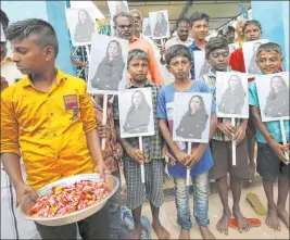  ?? Aijaz Rahi The Associated Press ?? A child holds a tray of chocolates as others hold portraits of Kamala Harris after special prayers ahead of her inaugurati­on, in Thulasendr­apuram, India.