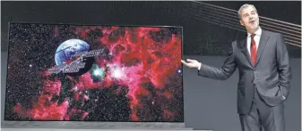  ?? DAVID BECKER, GETTY IMAGES ?? LG Vice President of Marketing David VanderWaal shows off the Signature 77-inch 4K HDR-enabled OLED TV.