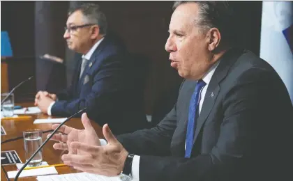  ?? JACQUES BOISSINOT/THE CANADIAN PRESS FILES ?? Premier François Legault responds to questions at a news briefing earlier this month, with Horacio Arruda, the director of public health, at his side. Legault’s government waited until Fête nationale to announce the end of daily COVID stats updates.