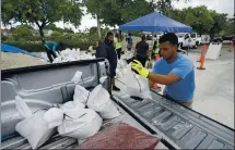  ?? WILFREDO LEE — THE ASSOCIATED PRESS ?? Miami workers load sandbags at a drive-thru sandbag distributi­on event for residents ahead of the arrival of rains associated with tropical depression Fred on Friday at Grapeland Park.