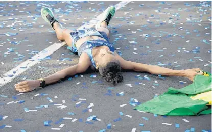  ?? PHELAN M. EBENHACK/ORLANDO SENTINEL ?? Top female finisher Giovanna Martins lies on the ground after crossing the finish line Sunday during the Walt Disney World Marathon.