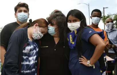  ?? Photos by Helen H. Richardson, The Denver Post ?? Beatriz Rangel, center, comforts her daughter Cynthia Rangel, left, during a rally for JBS plant workers who died of COVID-19 on June 28 in Greeley. Rangel's father, Saul Sanchez, was one of six workers at the JBS plant who died from the disease. He had worked for the plant for 30 years. Also in the photo are Adrian Rangel, 19, Sanchez’s grandson, left, and family friend Tatiana Haro, 13, right.