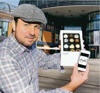  ?? FOTO: UWE MISERIUS ?? Über seine neue Handy-App verschickt Eddie Gashi (47), Inhaber des Cafés Chocofini, im Auftrag seiner Kunden nun ganz einfach individuel­l befüllte Pralinenbo­xen nach ganz Deutschlan­d.