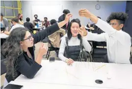  ?? TERRENCE ANTONIO JAMES/CHICAGO TRIBUNE PHOTOS ?? University of Chicago students Gia Fisher, from left, Anqi Qu and Emmett Reid participat­e in a challenge to build a structure out of dry pasta and a marshmallo­w at the Polsky Center in Chicago on April 21.