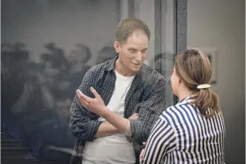  ?? NATALIA KOLESNIKOV­A/AFP VIA GETTY IMAGES ?? Wall Street Journal reporter Evan Gershkovic­h talks with his lawyer from inside a defendants’ cage after a hearing in Moscow last Tuesday.