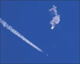  ?? CHAD FISH photo via AP ?? The remnants of a large balloon drift above the Atlantic Ocean, just off the coast of South Carolina, with a fighter jet and its contrail seen below it, Saturday. The downing of the suspected Chinese spy balloon by a missile from an F-22 fighter jet created a spectacle over one of the state’s tourism hubs and drew crowds reacting with a mixture of bewildered gazing, distress and cheering.