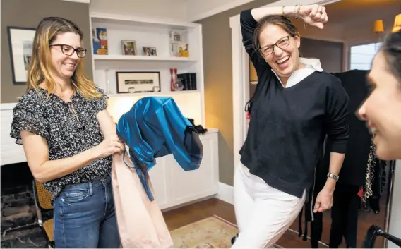  ?? Photos by Jana Asenbrenne­rova / Special to The Chronicle ?? Heather Howard (center), the hostess, jokes with Natasha Bradley (left), who holds a couple of Ruby Ribbon garments during an in-home demonstrat­ion in S.F.