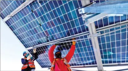  ?? WANG JIANG / FOR CHINA DAILY ?? Workers install photovolta­ic panels at a power farm in Zhangye, Gansu province, in November.