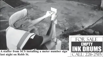  ??  ?? A staffer from SCS installing a meter number sign last night on Robb St.