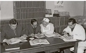  ?? FOTO: PICTURE ALLIANCE / DPA ?? Mitarbeite­r des DRK-Suchdienst­es suchen im Jahr 1962 gemeinsam mit Menschen, die Angehörige vermissen, im Rathaus Neukölln in Berlin Bildlisten mit Fotos von Vermissten ab.