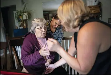  ?? PHOTOS BY WONG MAYE-E — THE ASSOCIATED PRESS ?? Betty Bednarowsk­i tries to argue with her daughter, Susan Ryder, left, and nursing assistant Arelis Estrella, center, against having her compressio­n stockings put on her legs, Nov. 30, in Rotterdam Junction, N.Y.