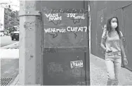  ?? CINDY ORD/GETTY IMAGES ?? A woman in a protective mask walks by a sign that reads “Wash hands, stay home, wear mask, clap at 7” in New York City on May 31.