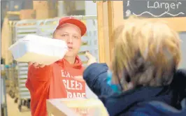  ?? JEFF VORVA/DAILY SOUTHTOWN ?? Witek’s Bakery manager Bart Bryniarski hands off a container of paczki to a customer in Palos Hills on Fat Thursday.