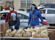  ??  ?? Yoseline Lopez, left, Sor Zulli and Steven Jerome volunteere­d their time to help distribute chickens and other food at the food giveaway event on Saturday.