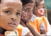  ??  ?? SOUTH AFRICA: Children have their faces painted with red ribbons in Soweto. Southern Africa is the part of the world hardest hit by AIDS.