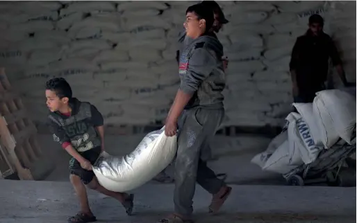  ?? AP ?? Palestinia­ns receive food aid at a UN warehouse in the Shati refugee camp, Gaza City. Across the Middle East, millions of people depend on UN support. —