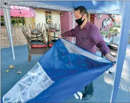  ?? Dan Watson/ The Signal ?? Kitchen Manager Joe Delgado takes down the sides of the outside dinning tent at Mimi’s Cafe in Valencia on Thursday, after L. A. County last week imposed a temporary ban on outdoor dining in an effort to mitigate the spread of COVID-19.