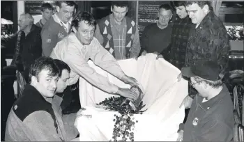  ?? 01_B10twe04 ?? Arran Mountain Rescue Team leader Alastair Hume breaks open a bottle from butcher Donald Mackay who collected £415.36 from customers for the team.