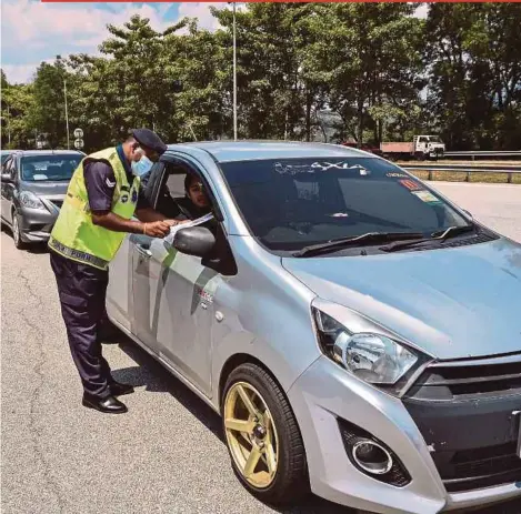  ?? BERNAMA PIC ?? A policeman checking a motorist’s travel documents at a roadblock at the Gombak toll plaza in Kuala Lumpur recently. Police are keeping a close watch on people who are trying to make interstate travel without permission.