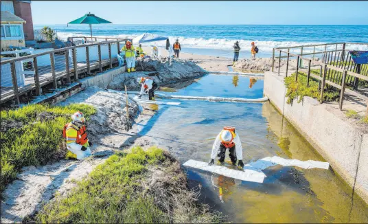  ?? Mark Rightmire The Associated Press ?? Crews use absorbent material Thursday to soak up oil that may have made its way into a creek in Laguna Beach, Calif.