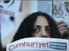  ??  ?? In this Oct. 31 file photo, demonstrat­ors hold placards and copies of the Cumhuriyet daily newspaper as they stage a protest outside a court where the trial of about a dozen employees of the newspaper on charges of aiding terror groups, continues in...