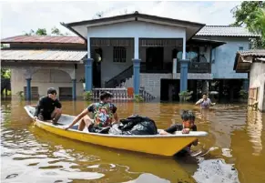  ?? — Bernama ?? To safety: residents using a boat to transfer their belongings to safer ground amid floods in Kampung bawah Lembah in Pasir Mas, Kelantan.