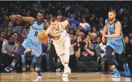  ?? Andres Kudacki / Associated Press ?? The Grizzlies’ James Ennis III, left competes for the ball with the Knicks’ Kristaps Porzingis, center, during the first half Wednesday night at Madison Square Garden.