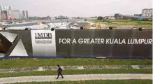  ??  ?? A man walking past a 1MDB billboard in Kuala Lumpur. The 1MDB board says it remains confident that it has not committed any wrongdoing. Reuters pic