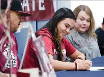  ?? RECORDER PHOTO BY CHIEKO HARA ?? Monache High School softball standout Chloe Rivas, center, signs the letter of intent for New Mexico State University as her father Mike, left, and mother Amy look on Wednesday at Monache High School.