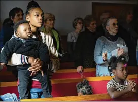  ?? ELISSA BENZIE / FOR THE AJC ?? Bria Thompson listens to the sermon with son Princeton and daughters Ka’liyah, 2, and Samyah, 5. Supporters were at the service, both inside and outside.