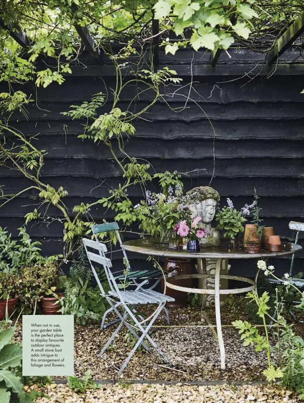  ??  ?? When not in use, your garden table is the perfect place to display favourite outdoor antiques. A small stone bust adds intrigue to this arrangemen­t of foliage and flowers.