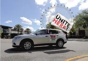  ?? RICARDO RAMIREZ BUXEDA/ORLANDO SENTINEL PHOTOS ?? Hospitalit­y workers hold a caravan along Internatio­nal Drive past The Wheel at Icon Park, to ask for unemployme­nt assistance and a safe return to work Monday.