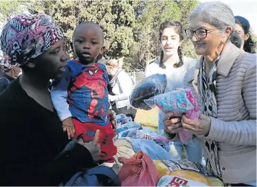  ?? Picture: FREDLIN ADRIAAN ?? GIFT OF WARMTH: Volunteer worker Mara du Piesanie gives some clothes to Joann Asan and her son Malipa at the Street Store pop-up shop held in Port Elizabeth at the weekend