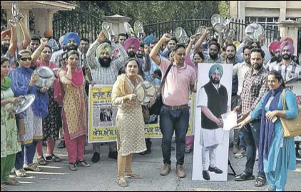  ?? HT FILE PHOTO ?? Teachers clinking utensils to stress that they are struggling due to nonpayment of salaries — over which two of them are seen ‘handing over’ a memo to the CM’S cutout — in Patiala.