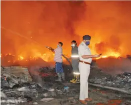  ?? — PTI ?? Fire fighters dose the fire which broke out at a slum area in Barola, Noida Sector 49 on Tuesday.