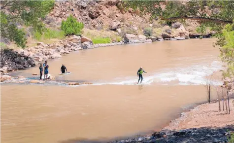  ?? EDDIE MOORE/JOURNAL ?? ABOVE: From left, Sarib Jot Khalsa and Sebastian Crespo, both of Santa Fe, and Erika and Ed Lucero, of Embudo, take turns surfing the new Abiquiú Wave on the Chama River near the Abiquiú Dam.
RIGHT: Sarib Jot Khalsa, of Santa Fe, surfs the wave on the Chama River, created to improve habitat for the river’s fish and other wildlife.