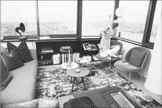  ??  ?? Penelope Green looks out of her window in her “test apartment,” with a view of the Hudson River and Lower Manhattan, at Urby in Jersey City, N.J. Urby is essentiall­y a convention­al apartment building with community features right out of the co-living playbook.