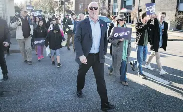  ?? — THE CANADIAN PRESS ?? Premier John Horgan walks to a mailbox with supporters posting their electoral reform referendum ballots after a rally in Vancouver on Sunday. Mail-in ballots must be received by Elections B.C. by 4:30 p.m. on Nov. 30.