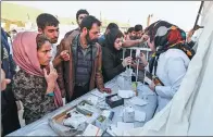  ?? ATTA KENARE / AGENCE FRANCE-PRESSE ?? Quake victims and survivors arrive to receive medical supplies at a field hospital in the town of Sarpol-e-Zahab, Iran, on Tuesday.