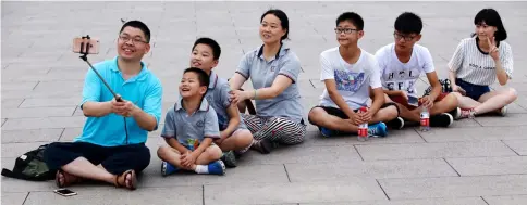  ??  ?? A family sits and poses for a selfie during a visit to Tiananmen Square in Beijing. — Bloomberg photo by Luke MacGregor