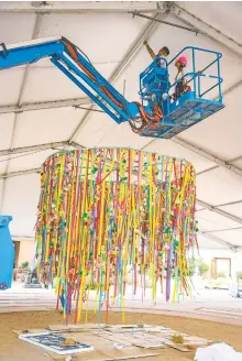  ?? GABRIELA CAMPOS/THE NEW MEXICAN ?? TOP LEFT: Andrea Soorikian, ambiance director, and her crew install an art piece Thursday resembling a chandelier made up of ribbons, flowers and butterflie­s in the center of the Innovation Tent for the 15th anniversar­y of the Internatio­nal Folk Art Museum.