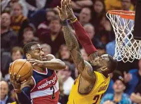  ?? AP PIC ?? Wizards’ John Wall (left) drives past Cavaliers’ LeBron James for a basket during their NBA game on Saturday.