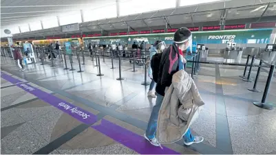  ?? David Zalubowski, The Associated Press ?? Travelers wear masks while passing the Frontier Airlines ticketing counter in the main terminal of Denver Internatio­nal Airport on Dec. 31.