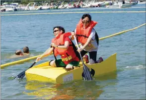  ?? FILE PHOTO ?? Terry Coughlin, left, and Bonnie Jeffcoat dip their oars to propel their Batwoman-themed Yellow Submarine to an exhausting finish during the 2017 World Championsh­ip Cardboard Boat Races.