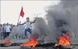  ?? PTI PHOTO ?? A protester jumps over burning tyres blocking National Highway-5 in Bhubaneswa­r during the nationwide strike by trade unions against the Centre’s polices, on Friday.