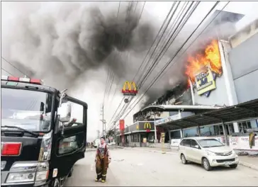  ?? MANMAN DEJETO/AFP ?? A firefighte­r stands in front of the burning shopping mall in Davao City, on the southern Philippine island of Mindanao, on Saturday.