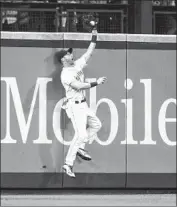  ?? Stephen Brashear Getty Images ?? ANDREW ROMINE of Seattle leaps for a catch at the left-field wall during the eighth inning Saturday.