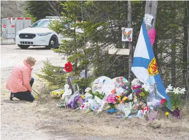  ?? ANDREW VAUGHAN / THE CANADIAN PRESS ?? A woman kneels to pay her respects at a roadblock in Portapique, N.S., on Wednesday, days after a man disguised as a Mountie went on a shooting rampage across the Maritimes province, killing at least 22 people.