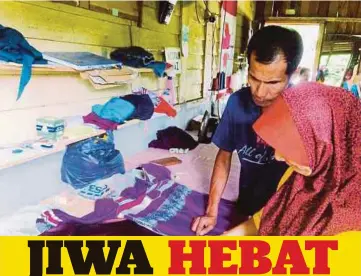  ??  ?? PASANGAN Wan Razlan dan Zawahir sibuk menyiapkan tempahan baju pelanggan.